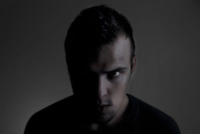 Portrait of angry young man against gray background