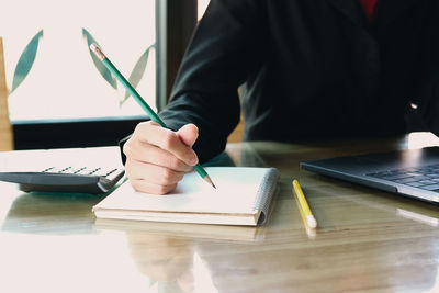 Midsection of man reading book on table