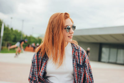 Smiling young woman wearing sunglasses while standing on street