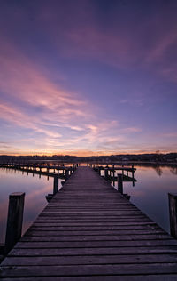 Pier over lake against sky during sunset