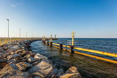 Pier over sea against clear blue sky