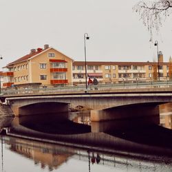 Bridge over river against sky in city