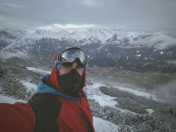 High angle view of man taking selfie while standing on snowcapped mountain