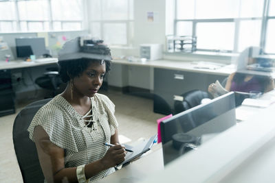 Female colleagues working at desk in office seen through glass window