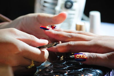 Cropped hand of beautician applying nail polish to woman