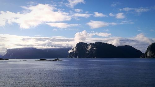 Scenic view of sea by mountains against sky