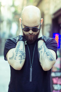 Thoughtful bald man standing on footpath