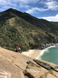 Rear view of people riding on mountain against sky