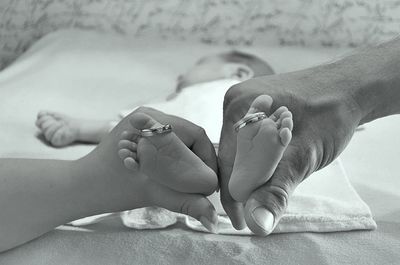 Cropped hands of parents holding baby feet at home