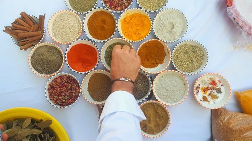 Cropped hand of man picking food from bowl on table