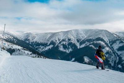 Rear view of man skiing on snowcapped mountains against sky