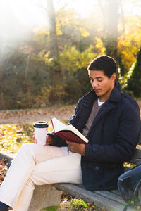 Young man sitting on table against trees