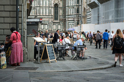 People on footpath and street in city