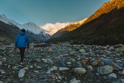 Rear view of man standing on rock against sky