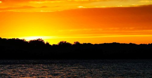 Scenic view of silhouette landscape against orange sky