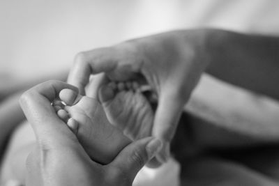 Cropped hands of mother making heart shape with child feet at home