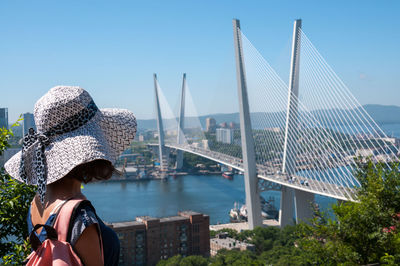 Rear view of woman against bridge against clear sky