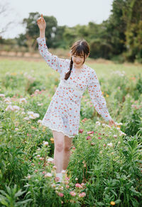 Full length of young woman standing amidst plants