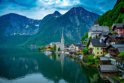 Town by lake and mountains against sky