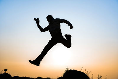 Silhouette man jumping against sky during sunset