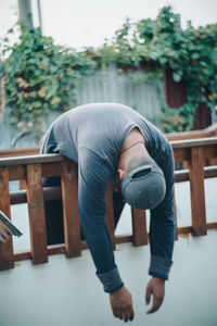 Man hanging on railing against plant