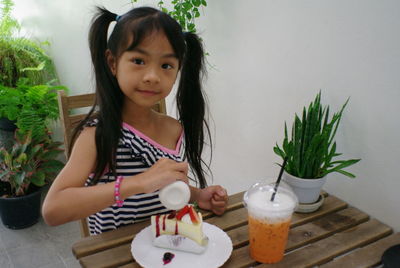 Portrait of girl holding ice cream on table