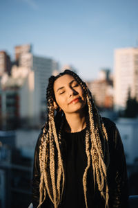 Beautiful young woman standing against city in background