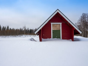 Snow covered houses and trees against sky