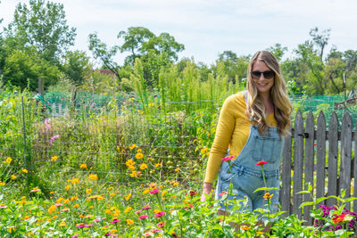 Portrait of smiling young woman standing by plants