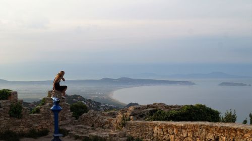 Rear view of woman overlooking calm sea