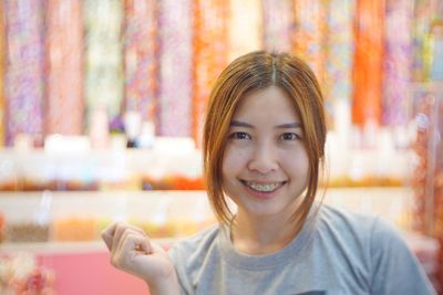 Close-up portrait of smiling young woman standing against illuminated wall