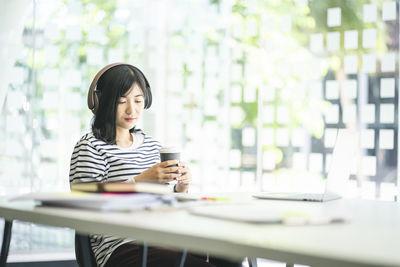 Woman using phone while sitting on table