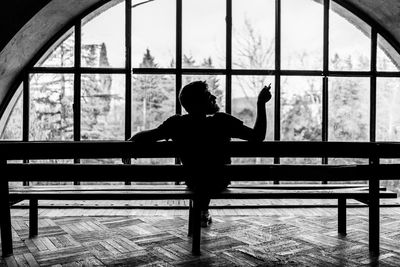 Rear view of silhouette woman standing in glass window