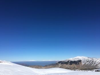 Scenic view of snowcapped mountains against clear blue sky