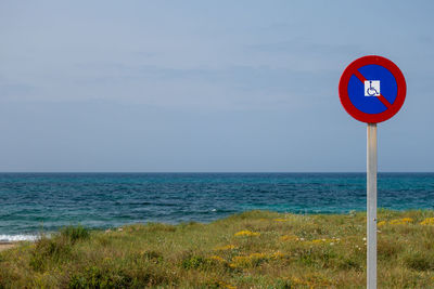 Road sign on beach against sky