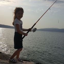 Portrait of girl fishing in sea against sky