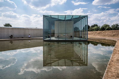 Reflection of swimming pool in lake against sky
