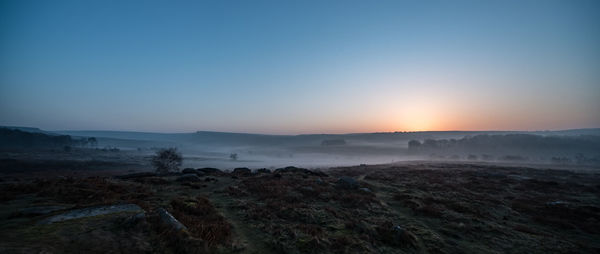 Scenic view of landscape against clear sky during sunset