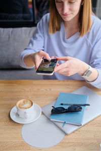 Girl taking photo of coffee cup and diary for social media