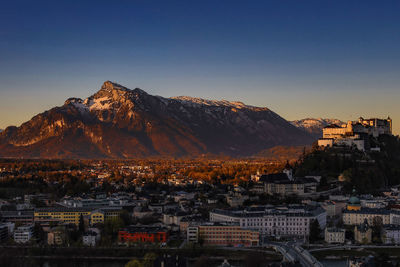 Aerial view of townscape by mountains against clear sky