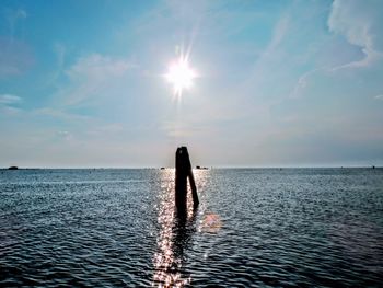 Silhouette person in sea against sky during sunset