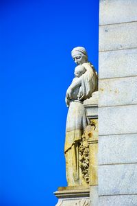 Low angle view of statue against building against clear blue sky