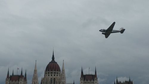 Low angle view of bird flying against cloudy sky