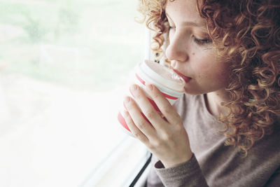 Woman drinking coffee by window