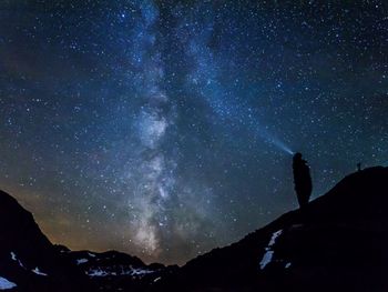 Low angle view of silhouette person on mountain against sky at night