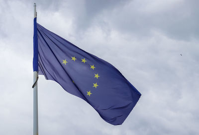 Spain flag at a flagpole moving in the wind against the sky