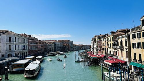 Boats moored in canal against clear blue sky