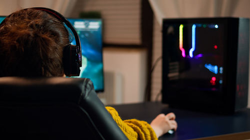 Rear view of woman playing video game at home