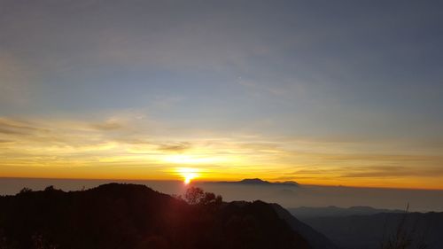 Scenic view of silhouette mountains against orange sky