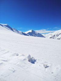 Scenic view of snowcapped mountains against blue sky